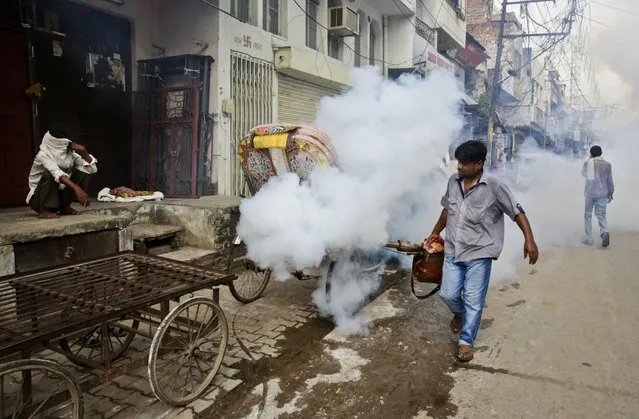 An Indian health worker fumigates an area in order to prevent the spread of mosquito-borne diseases in Allahabad, India, Wednesday, September 14, 2016. Despite efforts, including spraying vast areas with clouds of diesel smoke and insecticide, several Indian cities battle dengue fever and other mosquito-borne diseases like chikungunya every year during and after the rainy season. (Photo by Rajesh Kumar Singh/AP Photo)