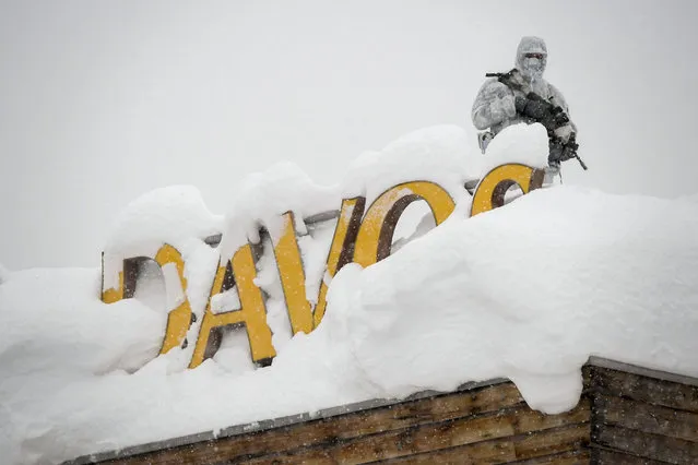 An armed Swiss police officer stands guard on the roof of a hotel near the congress center where the annual meeting of the World Economic Forum take place in Davos, Monday, January 22, 2018. The meeting brings together entrepreneurs, scientists, chief executives and political leaders from Jan. 23 to 26. (Photo by Fabrice Coffrini/AFP Photo)