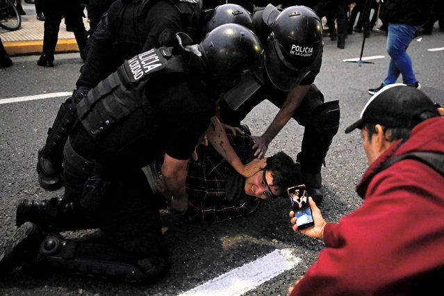 A demonstrator is controlled by policemen during a protest against Javier Milei's government cutbacks on the film institute funding, at the time the ultra-liberal “Decree of Necessity and Urgency” (DNU) is being debated, outside of the Gaumont cinema in front of the Congress in Buenos Aires, on March 14, 2024. Argentina's Senate rejected by 42 to 25 (with four abstentions) a massive deregulation package submitted by the government of President Javier Milei, the second legislative blow to his plans for drastic economic reform. (Photo by Luis Robayo/AFP Photo)