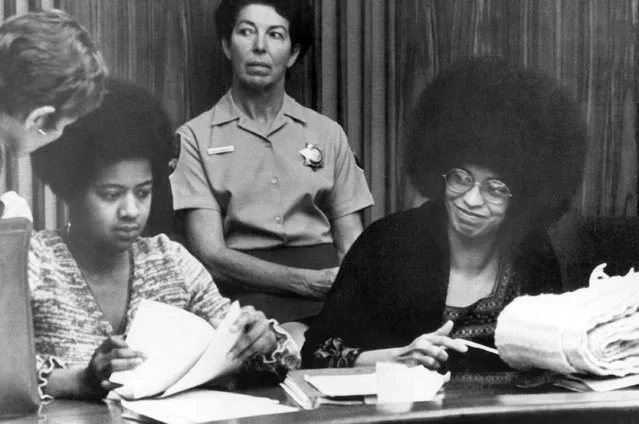 Angela Davis, in court in San Rafael, Calif., on October 19, 1971, on a change of venue hearing, smiles as a supporter in the courtroom shouts: “I love you, Angela. At left is Margaret Burnham, one of Miss Davis” attorneys. (Photo by AP Photo)