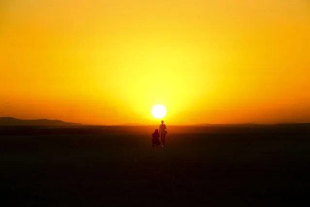 Silhouette of people are seen during the sunset in Lake Salt in Ankara, Turkey on August 07, 2020. Lake Salt is one of the most important wetlands and has a significant importance for the conservation of biodiversity in Turkey. (Photo by Halil Sagirkaya/Anadolu Agency via Getty Images)