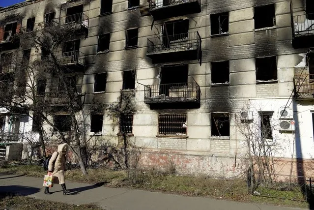 A woman walks past a destroyed apartment block in the Russian-controlled town of Severodonetsk in the eastern Lugansk region on January 24, 2023. (Photo by AFP Photo/Stringer)