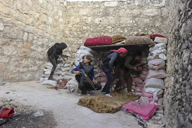 Rebel fighters take up position behind piles of sandbags on the Karm al-Tarab frontline, next to Aleppo International airport November 23, 2014. (Photo by Abdalrhman Ismail/Reuters)