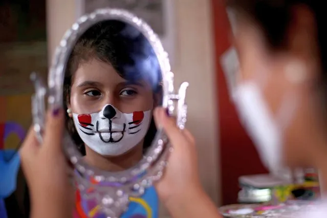 A girl looks at herself in the mirror after she had her face painted with a mask of a cartoon character by Palestinian artist Raneen Alzerie, who attempts to raise awareness of wearing face masks amid the coronavirus disease (COVID-19) crisis, in the southern Gaza Strip on September 21, 2020. (Photo by Ibraheem Abu Mustafa/Reuters)