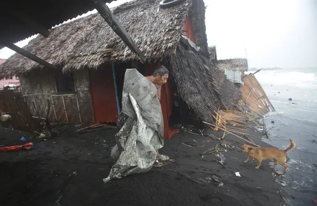 A Filipino man carries a dirty plastic sheet from his house after strong waves from Typhoon Hagupit battered a coastal village in Legazpi, Albay province, eastern Philippines on Monday, December 8, 2014. (Photo by Aaron Favila/AP Photo)