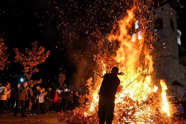 People attend the annual bonfire of dried oak branches, the Yule log symbol for the Orthodox Christmas eve, in front of the Orthodox cathedral in Podgorica on January 6, 2022. The branches are carried into the homes and burned on Orthodox Christmas Day, which is celebrated according to the Julian calendar, January 7, 2022. (Photo by Savo Prelevic/AFP Photo)