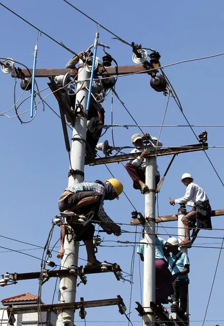 Labours work on electric power poles to modify and maintain the high voltage power cables in Mandalay, Myanmar, 17 October 2015. (Photo by Hein Htet/EPA)