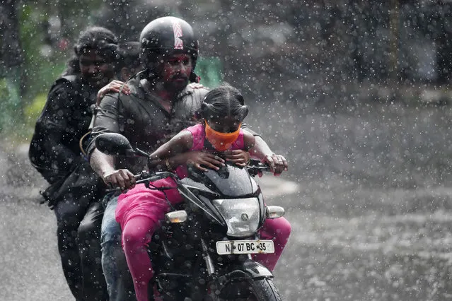 A family rides on a motorbike during a heavy rain shower in Chennai on November 18, 2020. (Photo by Arun Sankar/AFP Photo)