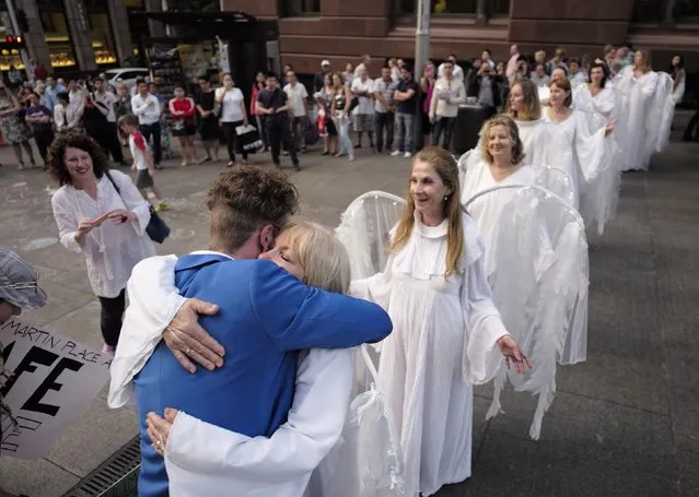 Women in angel costumes marching around the site of the Sydney cafe siege line up to receive an embrace from a man giving out “free hugs” to those mourning the victims of the incident in Sydney's Martin Place, December 18, 2014. Australian Prime Minister Tony Abbott on Wednesday ordered a sweeping investigation into a deadly hostage siege after tough new security laws and the courts failed to stop a convicted felon from walking into a Sydney cafe with a concealed shotgun. (Photo by Jason Reed/Reuters)