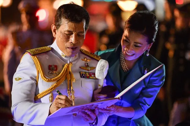 Thailand's King Maha Vajiralongkorn autographs a portrait brought it by royalists as Queen Suthida looks on during their appearance in Bangkok, Thailand, November 25, 2020. (Photo by Chalinee Thirasupa/Reuters)