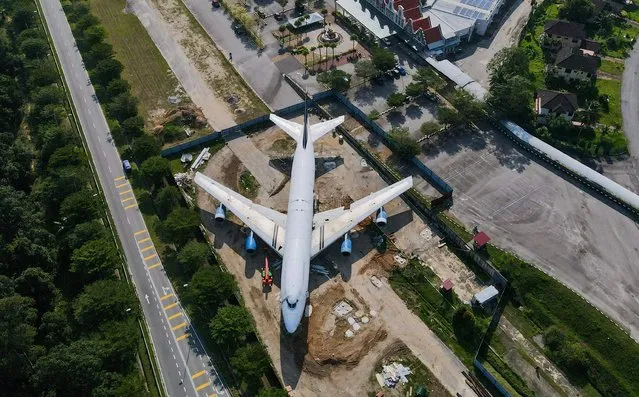An aerial view shows a decommissioned airplane at a construction site as it is being made into a tourist attraction near a theme park in Alor Gajah, Malaysia's Malacca state, on March 6, 2023. (Photo by Mohd Rasfan/AFP Photo)