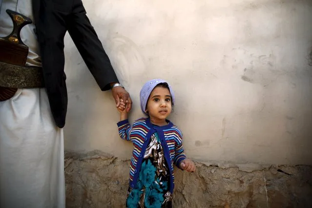 A girl holds her father's hand after she received polio vaccine drops during a house-to-house vaccination campaign in Yemen's capital Sanaa, November 10, 2015. (Photo by Khaled Abdullah/Reuters)