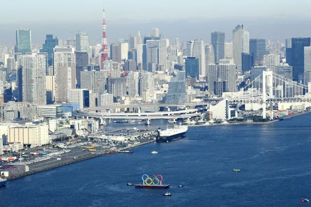 Photo taken December 1, 2020, from a Kyodo News helicopter shows the Olympic rings being transported ahead of their reinstallation in Tokyo Bay after undergoing a safety inspection and maintenance. The rings were temporarily removed in August following the Tokyo Summer Games' postponement until 2021 due to the coronavirus pandemic. (Photo by Kyodo News via Getty Images)