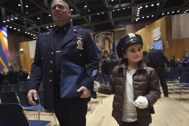 Karen Tanner, daughter of Nick Tanner, tries on his hat and gloves after her father was promoted to the rank of Detective Specialist during a New York Police Department Promotion Ceremony at Police Headquarters in the Manhattan borough of New York, December 19, 2014. (Photo by Carlo Allegri/Reuters)