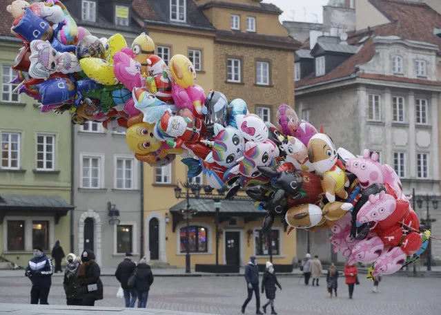 A balloon vendor waits for customers in usually bustling Warsaw's Castle Square that has few people now under anti-COVID-19 restrictions on New Year's Eve, in Warsaw, Poland, Thursday, December 31, 2020. (Photo by Czarek Sokolowski/AP Photo)