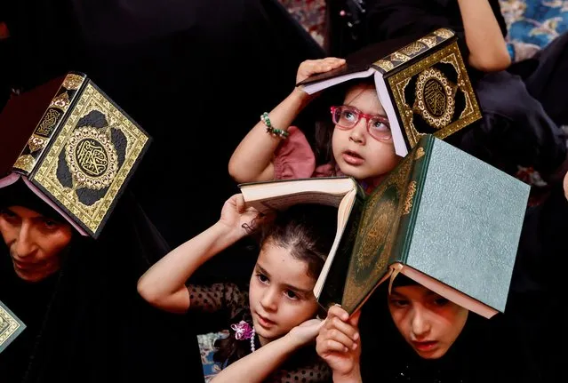 Shi'ite worshippers place copies of the Koran on their heads during the holy month of Ramadan, at Imam Ali Shrine in Najaf, Iraq on April 9, 2023. (Photo by Thaier Al-Sudani/Reuters)