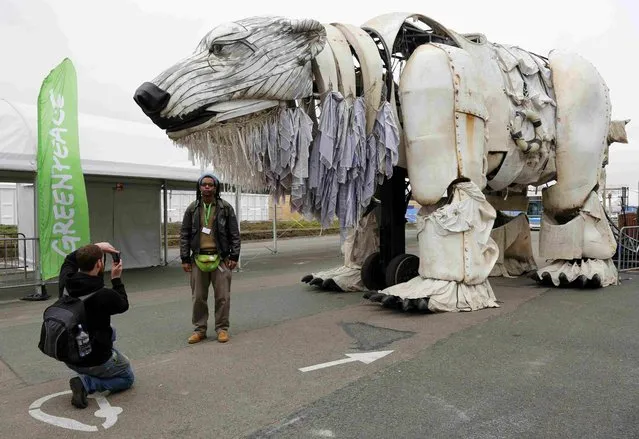 A man takes a photograph of a friend posing in front of Greenpeace's famous giant polar bear Aurora at the World Climate Change Conference 2015 (COP21) in Le Bourget, near Paris, France, December 11, 2015. (Photo by Jacky Naegelen/Reuters)