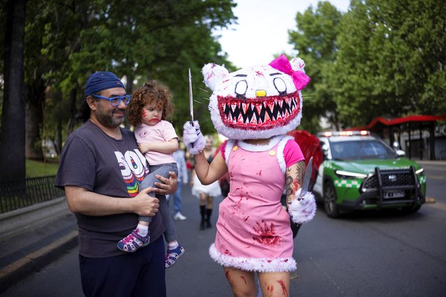 A man with a child looks at a participant dressed as Hello Kitty during the Zombie Walk, in Santiago, Chile, on October 20, 2024. (Photo by Pablo Sanhueza/Reuters)