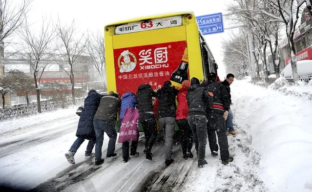 Residents push a bus which is stranded on a snow-covered street uphill as heavy snowfall hit Urumqi, Xinjiang Uighur Autonomous Region, China, December 11, 2015. (Photo by Reuters/Stringer)