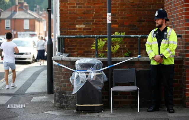 A British police officer guards a cordon around a plastic covered rubbish bin near John Baker House for homeless people in Salisbury, England, Thursday, July 5, 2018. British officials are seeking clues Thursday in the rush to understand how two Britons were exposed to the military-grade nerve agent Novichok. (Photo by Henry Nicholls/Reuters)
