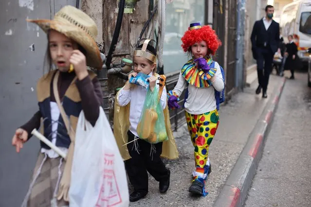 Boys wearing dress-up costumes to mark the upcoming Jewish holiday of Purim, which is a celebration of the Jews' salvation from genocide in ancient Persia, walk on a pavement in the ultra-Orthodox Jewish neighbourhood of Mea Shearim in Jerusalem on February 24, 2021. (Photo by Ammar Awad/Reuters)