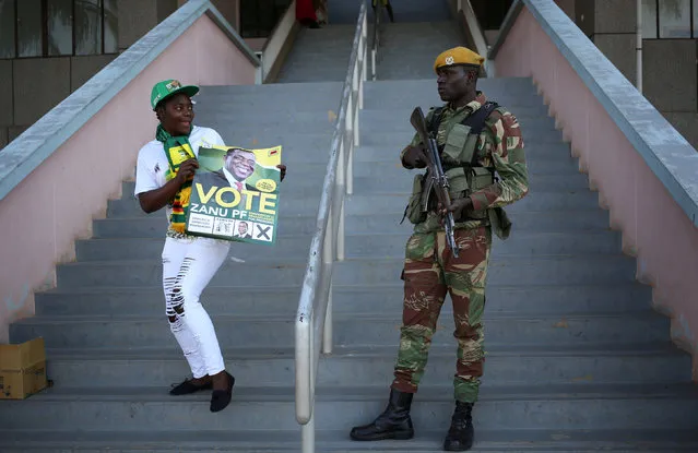 A ZANU PF supporter holds a poster in front of a Military officer ahead of  a rally in the capital Harare, Zimbabwe, July 28, 2018. (Photo by Siphiwe Sibeko/Reuters)