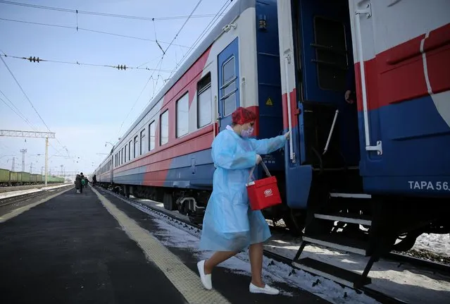 A medical worker carries a bag containing doses of the Sputnik V vaccine against the coronavirus as she enters a carriage of the Academician Fyodor Uglov medical train, at a railway station in the town of Tulun in Irkutsk Region, Russia on March 16, 2021. (Photo by Evgeny Kozyrev/Reuters)