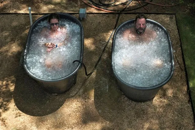 Allison Callender and Kent Willis, members of Mekanix Gym, a total wellness center, take a cold plunge in ice after a workout at the gym's Shadow Sanctuary facility during hot weather in Houston, Texas, U.S., July 19, 2023. (Photo by Adrees Latif/Reuters)