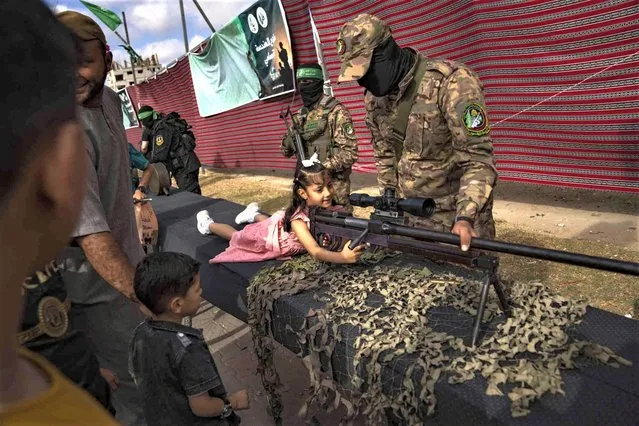 A Palestinian child poses with a weapon at an arms show for the ruling Hamas group's military wing at Nusseirat refugee camp, central Gaza Strip, Friday, June 30, 2023. (Photo by Fatima Shbair/AP Photo)