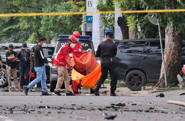 Police officer and rescue workers carry a body bag containing what is believed to be human remains outside a church where an explosion went off in Makassar, South Sulawesi, Indonesia, Sunday, March 28, 2021. A suicide bomber blew himself up outside a packed Roman Catholic cathedral on Indonesia's Sulawesi island during a Palm Sunday Mass, wounding a number of people, police said. (Photo by Masyudi S. Firmansyah/AP Photo)