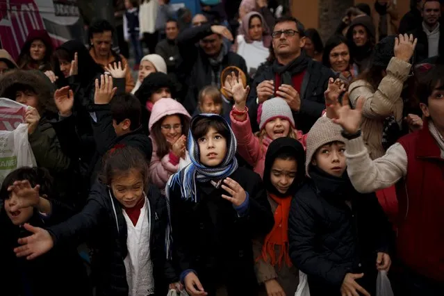 People react as sweets are thrown to them from a float by actors dressed as the Three Wise Men during the traditional Epiphany parade in Malaga, southern Spain, January 5, 2016. Children in Spain traditionally receive their Christmas presents delivered by the Three Wise Men on the morning of January 6, during the Christian holiday of the Epiphany. (Photo by Jon Nazca/Reuters)