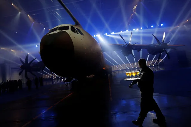 A waiter walks past an Airbus A400M military transport plane is parked at the Airbus assembly plant during an event in the Andalusian capital of Seville, southern Spain, December 1, 2016. (Photo by Marcelo del Pozo/Reuters)