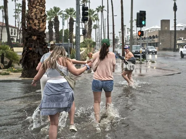 Tourists from Arkansas walk through the flooded streets of downtown Palm Springs, California on August 20, 2023. Southern California is under a tropical storm warning which could bring heavy rains, high winds and flooding. (Photo by Philip Cheung for The Washington Post)