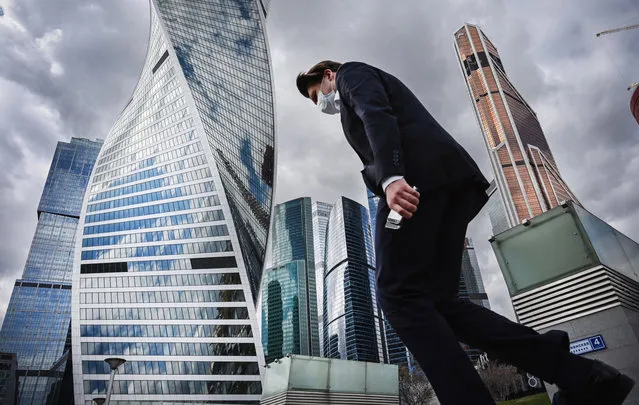 A clerk wearing a face mask walks in Moscow's International Business Centre (Moskva City) in Moscow on April 26, 2021, amid the ongoing Covid-19 pandemic. (Photo by Alexander Nemenov/AFP Photo)