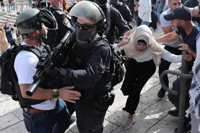A Palestinian woman runs near Israeli security force members during scuffles amid Israeli-Palestinian tension as Israel marks Jerusalem Day, at Damascus Gate just outside Jerusalem's Old City on May 10, 2021. (Photo by Ronen Zvulun/Reuters)