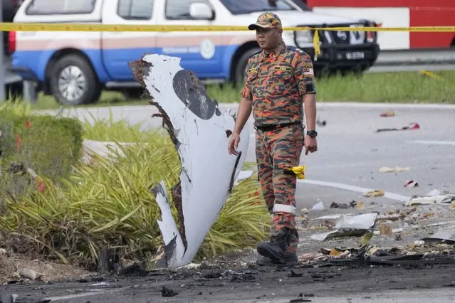A member of the fire and rescue department inspect the crash site of a small plane in Shah Alam district, Malaysia, Thursday, August 17, 2023. Police say a small aircraft has crashed in the suburb of Malaysia's central Selangor state, with multiple bodies recovered. (Photo by Vincent Thian/AP Photo)