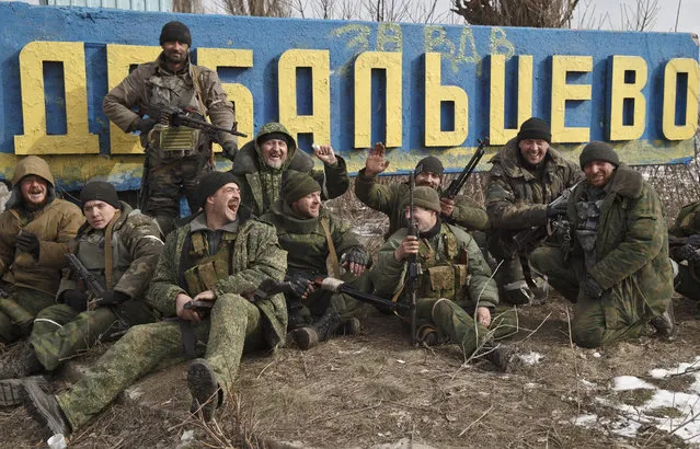 Russia-backed rebels pose by a road sign at the entrance in Debaltseve, Ukraine, Friday, Feb. 20, 2015, after checking the access road into town for mines left behind by retreating Ukrainian government troops. After weeks of relentless fighting, the embattled Ukrainian rail hub of Debaltseve fell Wednesday to Russia-backed separatists, who hoisted a flag in triumph over the town. The Ukrainian president confirmed that he had ordered troops to pull out and the rebels reported taking hundreds of soldiers captive. (AP Photo/Vadim Ghirda)
