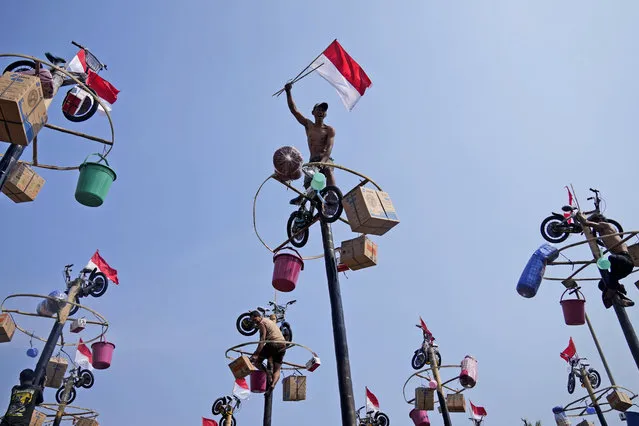 A participant celebrates after reaching the prizes during a greased-pole climbing competition held as a part of the Independence Day celebrations at Ancol Beach in Jakarta, Indonesia, Thursday, August 17, 2023. Indonesia is celebrating its 78th independence from the Dutch colonial rule. (Photo by Dita Alangkara/AP Photo)