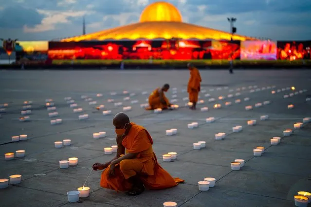 Buddhist monks wearing face masks light candles during Vesak Day, an annual celebration of Buddha's birth, enlightenment, and death at the Dhammakaya temple amid the coronavirus disease (COVID-19) pandemic in Pathum Thani province, Thailand, May 26, 2021. (Photo by Athit Perawongmetha/Reuters)