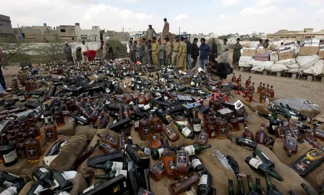 Customs officials and media gather around a pile of narcotics and liquor as confiscated contraband is prepared to be burned and destroyed during a campaign marking International Customs Day in Karachi, Pakistan January 26, 2016. (Photo by Akhtar Soomro/Reuters)