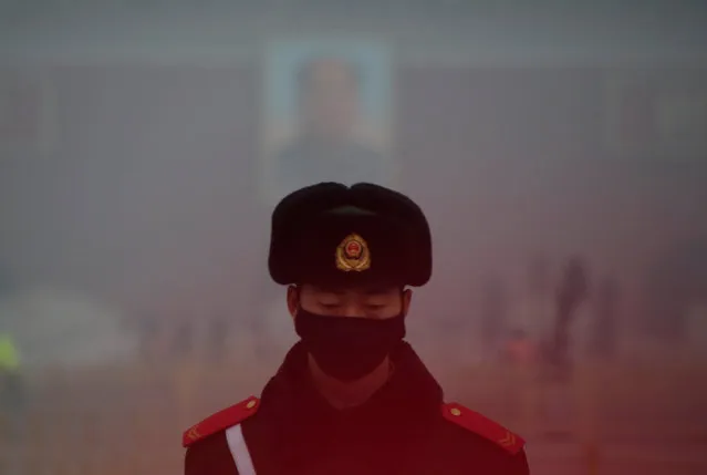 A paramilitary police officer wearing a mask stands guard in front of a portrait of the late Chairman Mao Zedong during smog at Tiananmen Square after a red alert was issued for heavy air pollution in Beijing, China, December 20, 2016. (Photo by Jason Lee/Reuters)