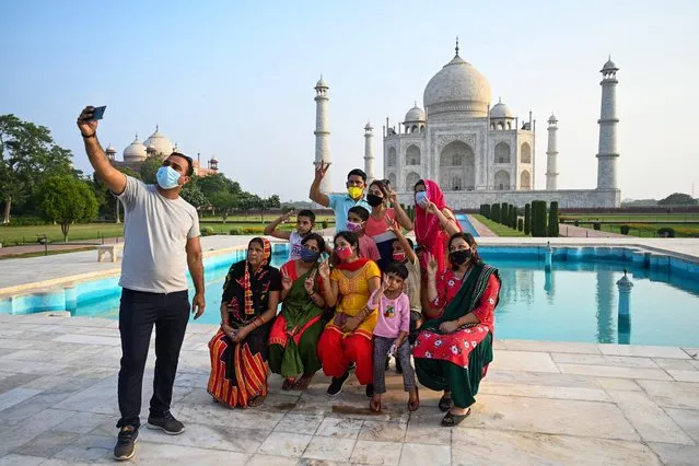 A group of tourists take souvenir photos at the Taj Mahal after it reopened to visitors following authorities easing Covid-19 coronavirus restrictions in Agra on June 16, 2021. (Photo by Money Sharma/AFP Photo)
