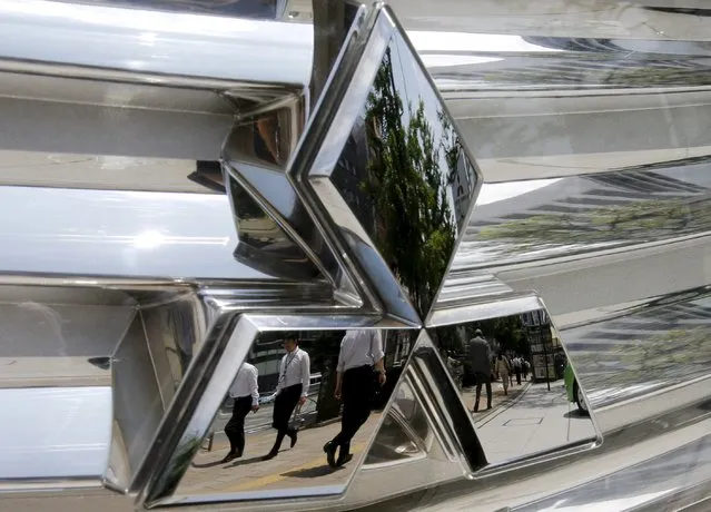 Passers-by are reflected on the logo of a Mitsubishi Motors Corp's car at the company headquarters in Tokyo in this May 23, 2013 file photo. Mitsubishi Corporation is expected to report results this week. (Photo by Toru Hanai/Reuters)