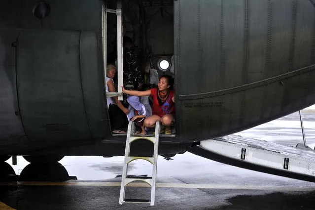 Residents aboard a government plane wait for family members, before leaving the devastated city of Tacloban. (Photo by Jes Aznar/The New York Times)