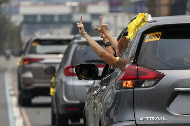 Supporters of former Philippine President Benigno Aquino III flash the “L” sign meaning “Fight!” from a vehicle window during a motorcade before his burial in Quezon City, Philippines on Saturday, June 26, 2021. (Photo by Basilio Sepe/AP Photo)