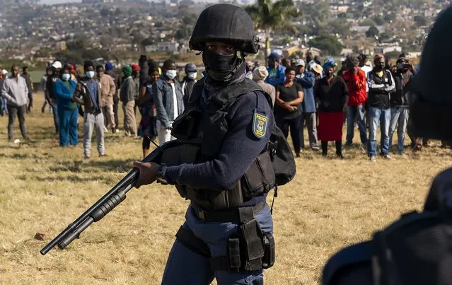 An armed policeman patrols as Police Minster Bheki Cele visits Phoenix, a neighbourhood severely affected by unrest and racial tensions near Durban, South Africa, Saturday, July 17, 2021. South African President Cyril Ramaphosa has vowed to restore order to the country after the week of violence set off by the imprisonment of former President Jacob Zuma. (Photo by Shiraaz Mohamed/AP Photo)