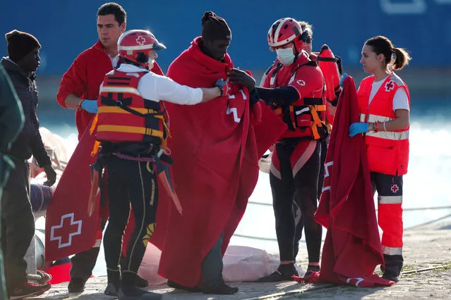 Migrants, who are part of a group intercepted aboard a dinghy off the coast in the Mediterranean sea, are assisted by members of Spanish Red Cross after arriving on a rescue boat at a port in Malaga, southern Spain, January 1, 2017. (Photo by Jon Nazca/Reuters)