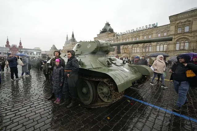 People pose for a photo in front of a Soviet era T-34 tank at an open air interactive museum to commemorate the 82nd anniversary of the World War II-era parade, at Red Square, in Moscow, Russia, on Monday, November 6, 2023. (Photo by Alexander Zemlianichenko/AP Photo)