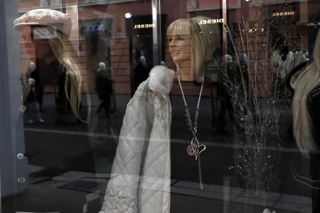 Participants dressed in black, wearing masks, beating drums and pushing small carts making a synchronized and loud sound are reflected in a shop window as they take part in an Easter procession marching through the streets of Ceske Budejovice, Czech Republic, Friday, April 2, 2021. (Photo by Petr David Josek/AP Photo)