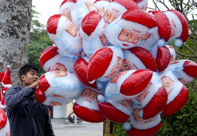 A street vendor sells “Santa” balloons on a street corner in Hoi An, Vietnam, Wednesday, December 25, 2013. (Photo by Mark Baker/AP Photo)